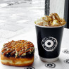 Svart dobbeltlags pappkrus med 'Black box donuts' logo som brukes til å servere en kopp varm kakao